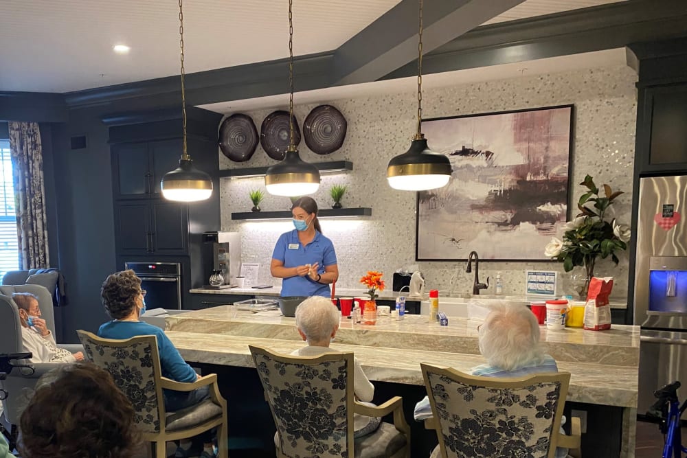 Masked nurse talking to a group of residents in a cafe at a Anthology of Highland Park location