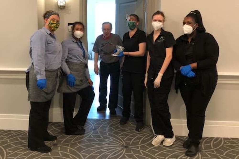 Group of masked caretakers greeting a resident at their door at a Anthology of Highland Park community