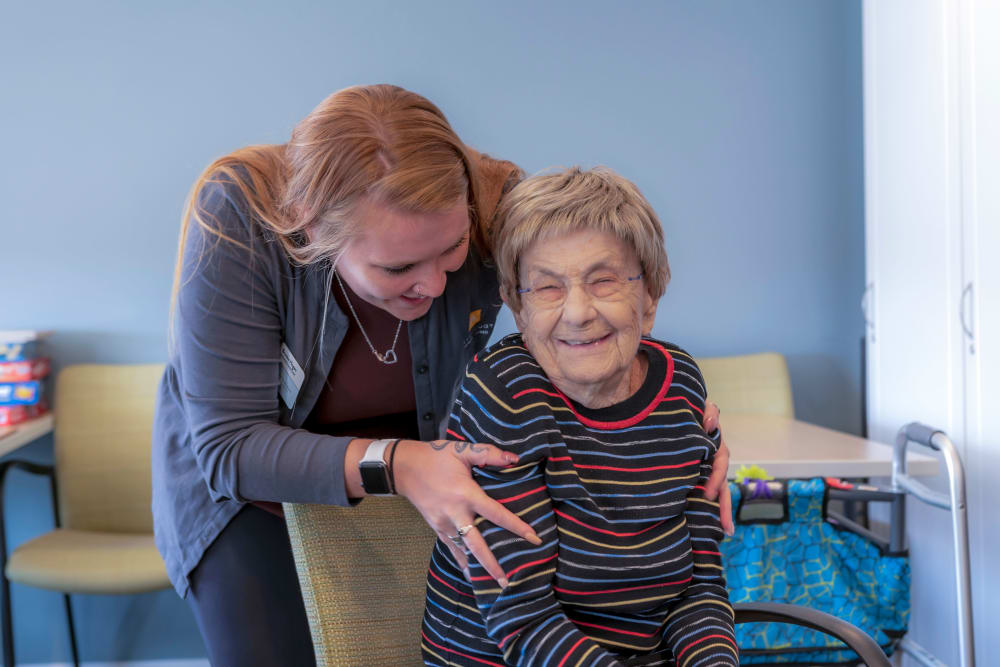 Masked nurse talking to a group of residents in a cafe at a Anthology Senior Living location